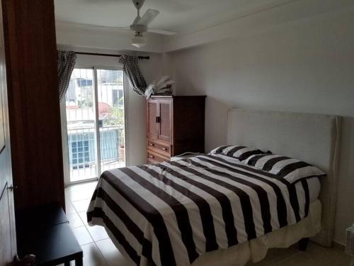 1 dormitorio con cama de rayas en blanco y negro y ventana a COZY AND LOVELY APARTMENT, en Santo Domingo