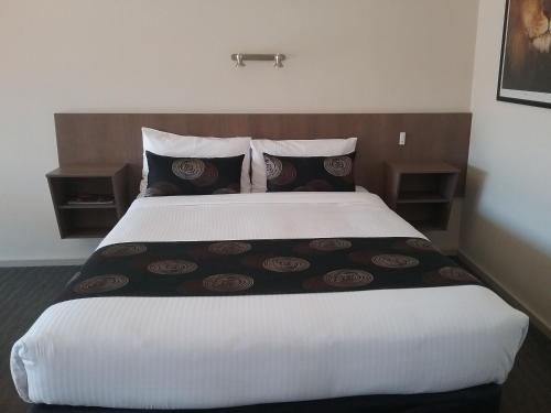 a bedroom with a large white bed with pillows at Werribee Park Motor Inn in Werribee