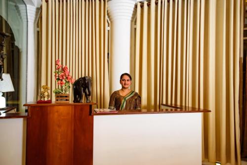 a woman standing behind a counter in a room with curtains at Kandy view resort in Kandy