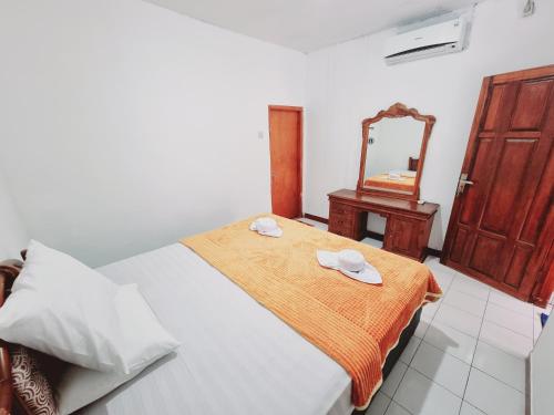 a bedroom with a bed and a mirror in it at Pandu Homestay Mandalika Lombok in Kuta Lombok