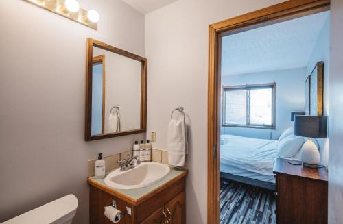 a bathroom with a sink and a mirror and a bed at Aurora Bayside Inn in Yellowknife