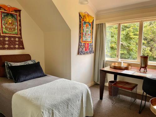 um quarto com uma cama, uma secretária e uma janela em Nyima Tashi Buddhist Centre em Auckland