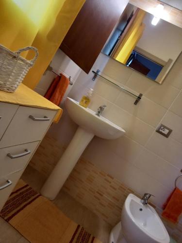 een badkamer met een wastafel, een toilet en een spiegel bij asfodelo in Villaputzu