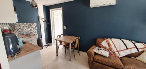 a living room with a couch and a table at Le Nid'Isle - Stationnement privé gratuit - Wi-Fi performant - Climatisation in LʼIsle-sur-la-Sorgue