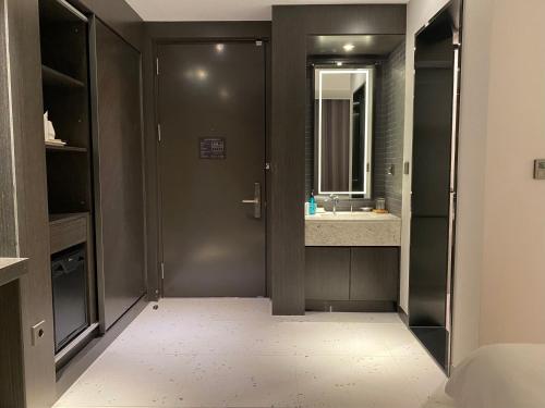 a bathroom with a door and a sink and a mirror at Hotel Avenue in Changwon
