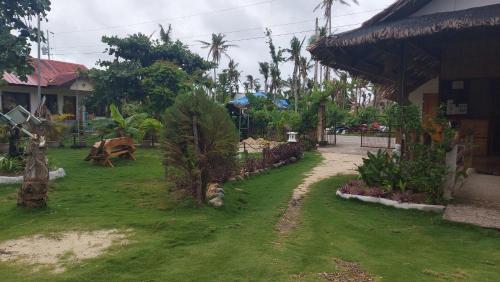 a yard with green grass and trees and a building at Gardenview Homestay Siargao in General Luna
