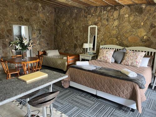 een slaapkamer met een bed en een tafel en een tafel bij Uitzicht Private Nature Reserve and Lodge in Fouriesburg