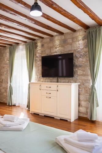 a living room with a tv on a stone wall at Stephane City Vibe Suites in Trogir