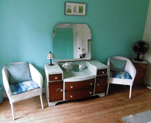 - une chambre avec un lit avec un miroir et deux chaises dans l'établissement La Bicyclette Bleue, à Montpinchon