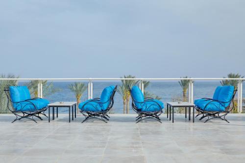 Pickalbatros Royal Grand Sharm - Adults Friendly 16 Years Plus في شرم الشيخ: مجموعة من الكراسي الزرقاء والطاولات أمام المحيط