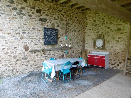 Cette chambre est dotée d'une table et de chaises dans un mur en pierre. dans l'établissement La Bicyclette Bleue, à Montpinchon