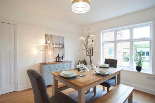 uma sala de jantar com uma mesa de madeira e cadeiras em Doctors lane Stylish 3 Bedroom Family House with Parking em Melton Mowbray