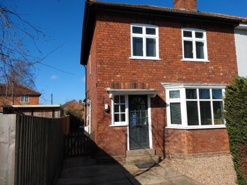 a red brick house with a white door at Doctors lane Stylish 3 Bedroom Family House with Parking in Melton Mowbray