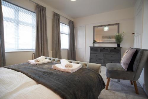 a bedroom with a bed and a chair and a mirror at Doctors lane Stylish 3 Bedroom Family House with Parking in Melton Mowbray