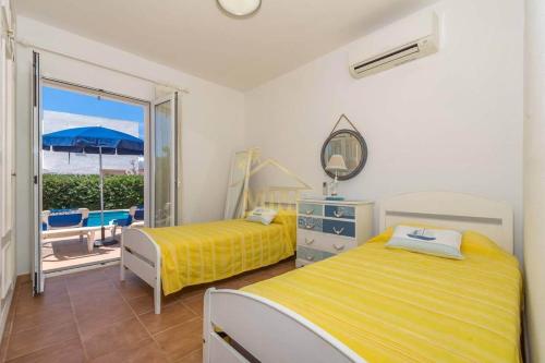 a bedroom with two beds and a view of the beach at Villa ADELE Binibeca sea view in Binibeca