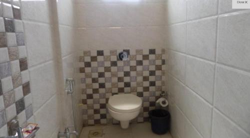 a small bathroom with a toilet and a tiled wall at Hotel SaiPrasad Executive Solapur in Solapur
