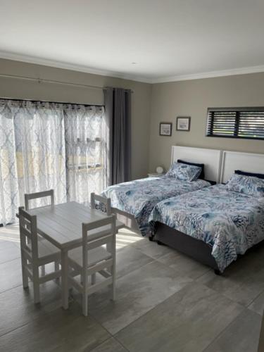 a bedroom with two beds and a table and chairs at Idiaz Beach House in Mossel Bay