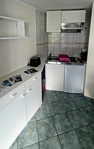 eine Küche mit weißen Schränken und Fliesenboden in der Unterkunft Miniferienhaus Bad Elster in Bad Elster