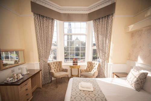 a bedroom with a bed and two chairs and a window at Clifton Park Hotel - Exclusive to Adults in Lytham St Annes