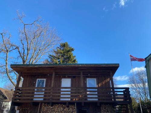 a log cabin with a flag in front of it at Viesu Māja Arnicāni in Ragaciems