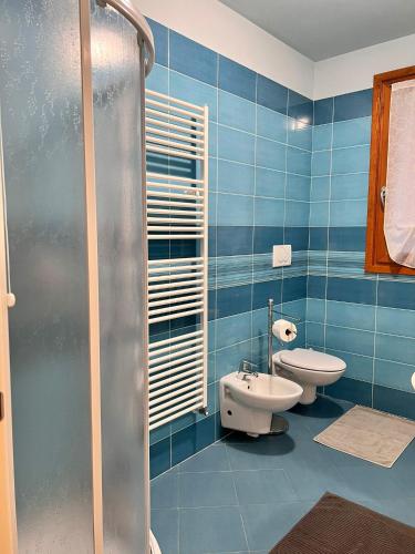 a blue tiled bathroom with a toilet and a sink at Appartamento Emerald in Sirmione