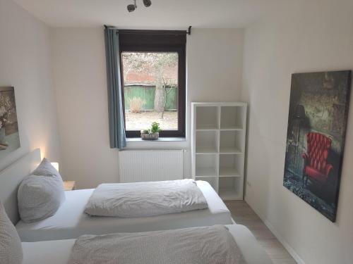 a white bedroom with a bed and a window at FeWo Engler Lauenburg Bahnhofstraße in Lauenburg