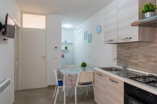 a kitchen with a table with chairs and a sink at Suite LA CONCHIGLIA località Caccia e Riserva in Santa Marinella