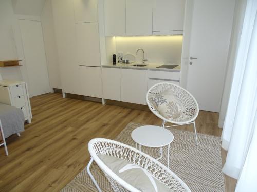 a kitchen with two white chairs and a table at Casa do Largo in Nazaré