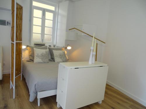 a bedroom with a white bed and a white dresser at Casa do Largo in Nazaré