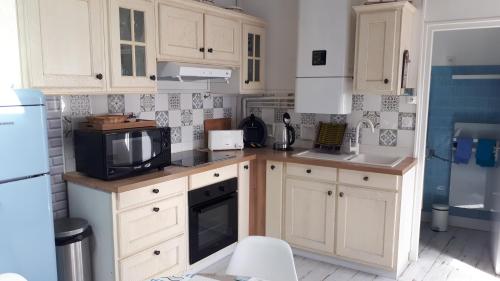 a kitchen with white cabinets and a tv on a counter at Maison typique vendéenne in La Tranche-sur-Mer