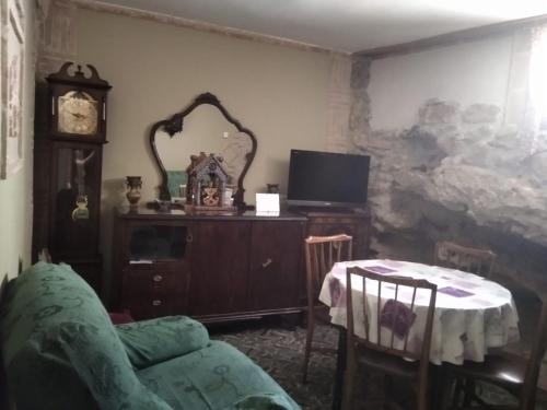 uma sala de estar com uma mesa, uma cadeira e um relógio em La casita del herrador em El Burgo de Osma