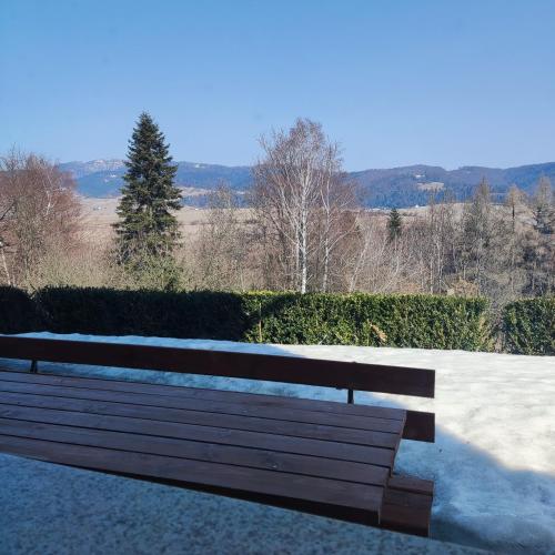 a wooden bench sitting on top of a sidewalk at Apartament w ogrodzie in Tylka