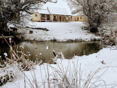 a house in the snow with a pond in front at Ratho Farm in Bothwell