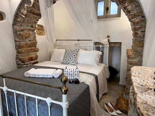 um quarto com uma cama num quarto com uma parede de pedra em PETRA HOME heritage and hospitality em Apérathos