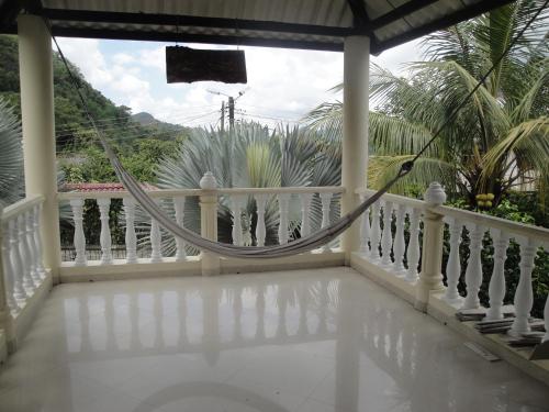 a porch with a hammock on a white railing at Casa de Huespedes Villa Hermosa in La Vega