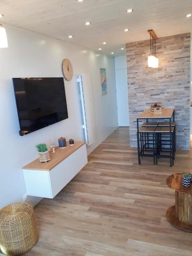 un salon avec une télévision à écran plat sur un mur dans l'établissement Magnifique Studio Face Mer avec Place Privative., à Saint-Jean-de-Monts