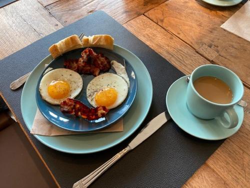 a plate of eggs and bacon and a cup of tea at Rouleur Houffalize in Houffalize
