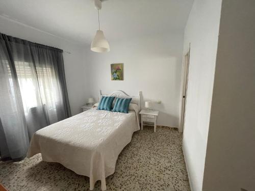a white bedroom with a bed with blue pillows at Apartamento Antonia muy cerca de la playa in Bolonia