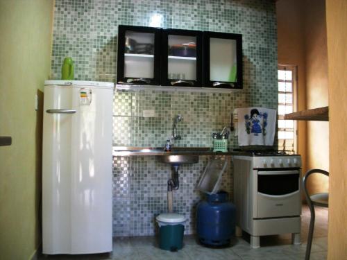 a small kitchen with a refrigerator and a sink at Casinhas na Praia do Julião em Ilhabela SP in Ilhabela