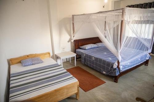 a bedroom with two beds and a canopy bed at Kodi Beach Home in Galle