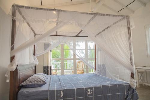 1 dormitorio con cama con dosel y ventana en Kodi Beach Home, en Galle