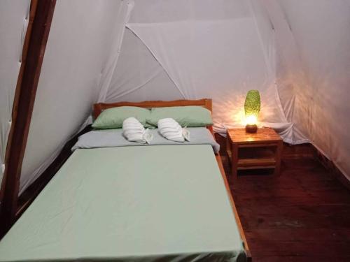 a bed in a tent with a lamp on a table at SHUKRAN Apartelle in Siquijor