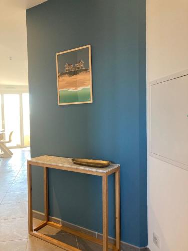 una mesa en una habitación con una pared azul en Superbe appartement rénové, parking et terrasse en Biscarrosse