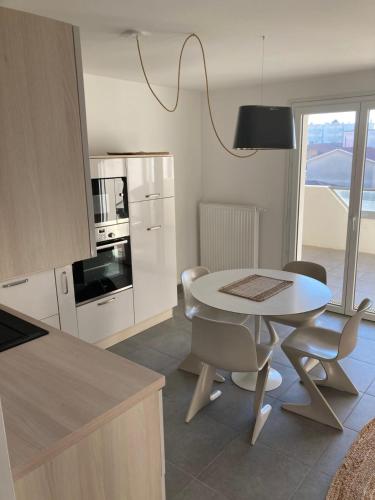 una cocina con mesa y sillas blancas y una mesa y una cocina con en Superbe appartement rénové, parking et terrasse en Biscarrosse