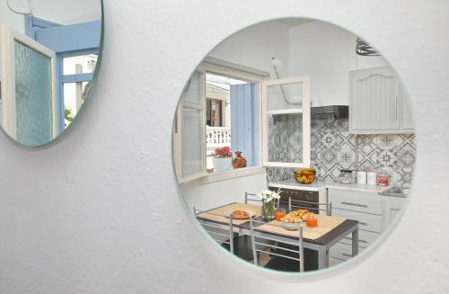 a white kitchen with a table and a mirror at Vanilla guesthouse in Skopelos Town