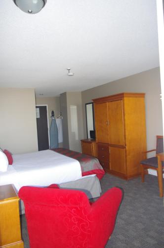 a hotel room with a bed and a red chair at South Hill Lodge in Prince Albert