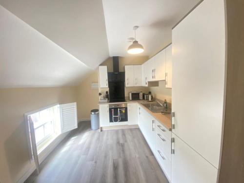 a kitchen with white cabinets and a wooden floor at Hodge Bower Holidays - Ironbridge, Squires in Ironbridge