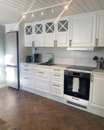 a kitchen with white cabinets and a stove and refrigerator at Gårdshuset mitt i centrala Gävle in Gävle