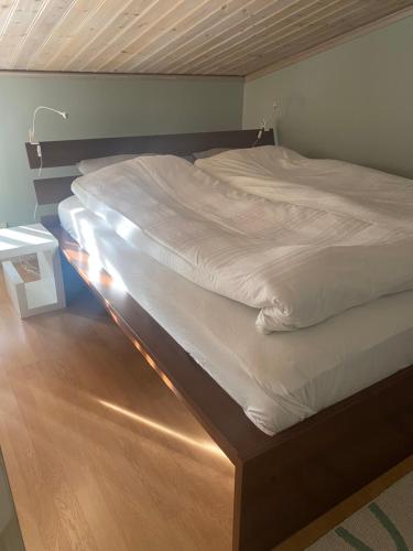 uma cama com lençóis brancos e uma cabeceira de madeira em Gårdshuset mitt i centrala Gävle em Gävle