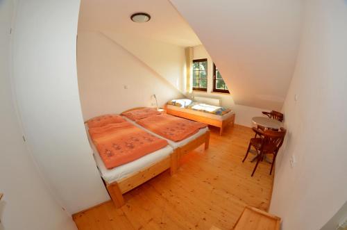 Schlafzimmer im Dachgeschoss mit einem Bett und einem Tisch in der Unterkunft Penzion Pod pralesem in Lenora